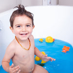 Youngster in blue bath with rubber ducks